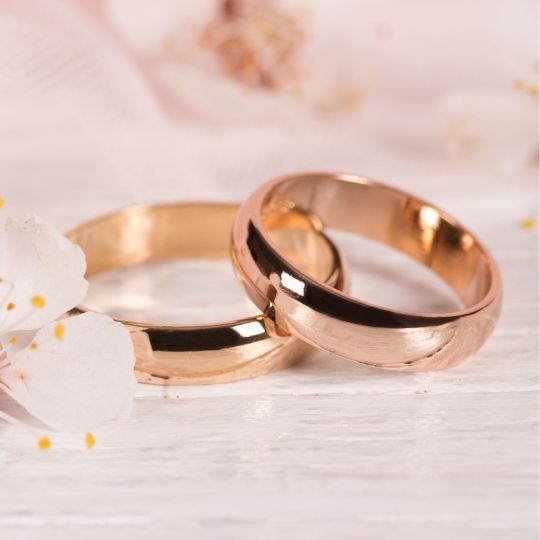 two
                        gold wedding rings on a pink background