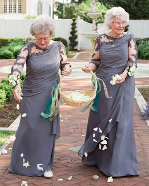 Grandma flower girls
                      wearing matching slate blue gowns and scattering
                      white rose petals