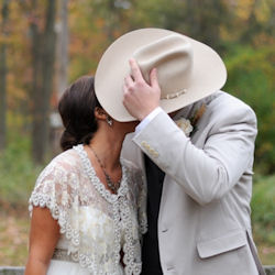 Groom kissing bride behind hat