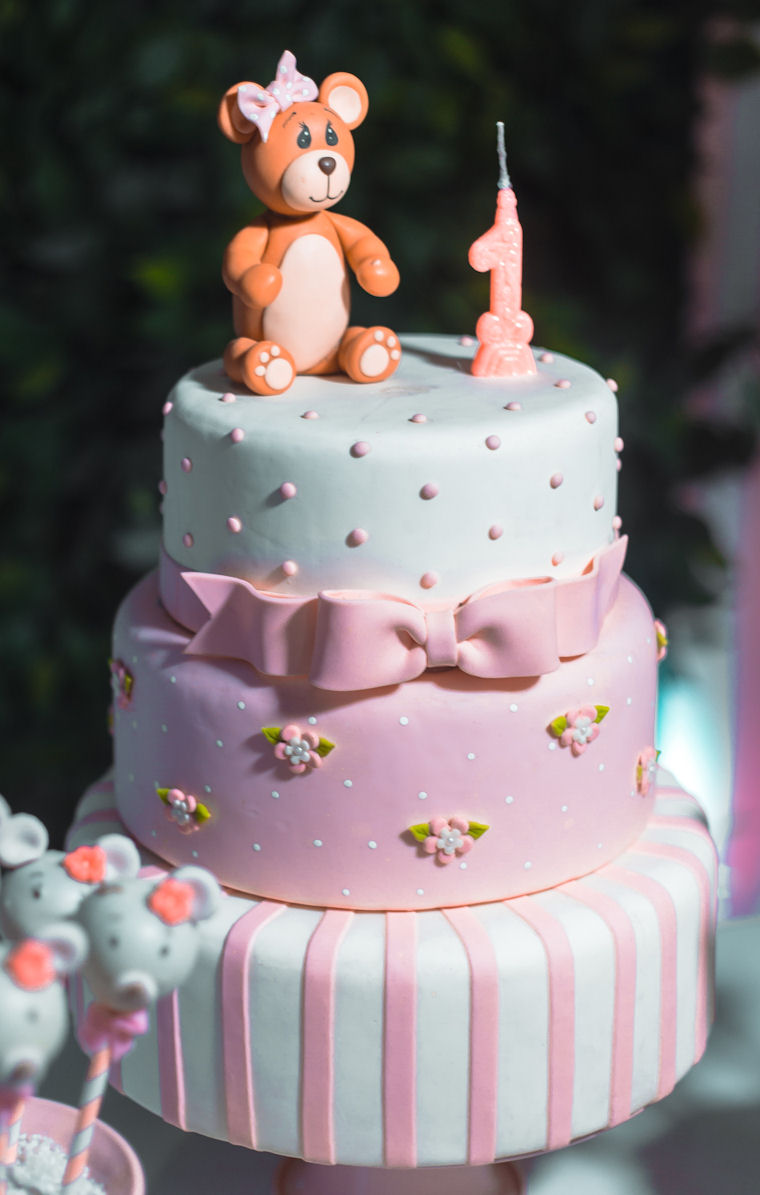 Three tier birthday cake
                    with pink, white and blue icing, the numeral 1 and a
                    teddy bear on the top