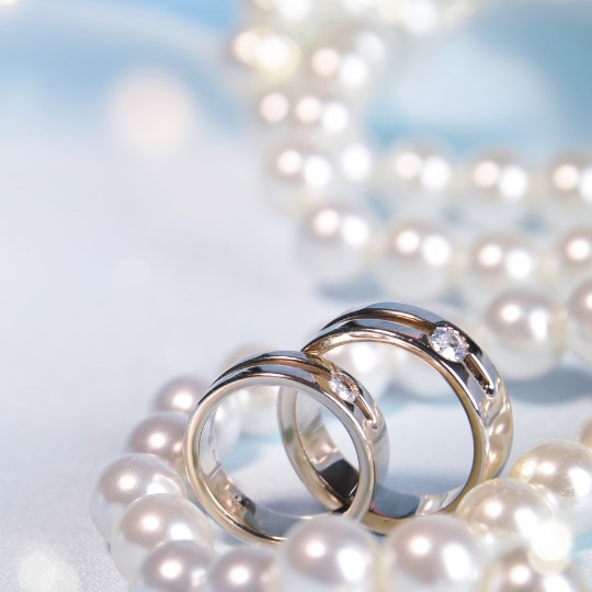 A String of pearls with two platinum
                              wedding rings, each set with one diamond,
                              on a blue background