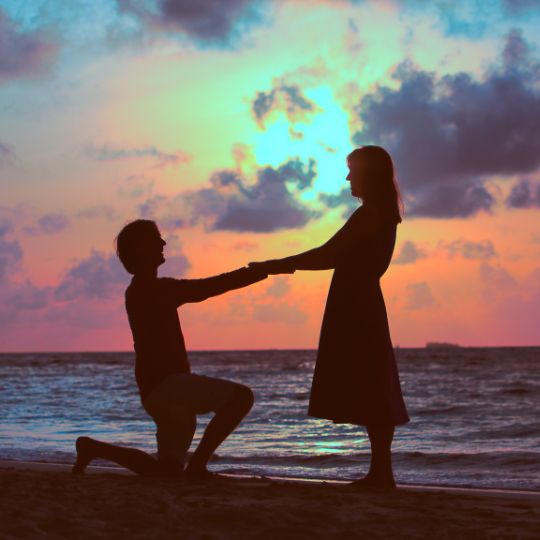 Proposal against a sunset sky. One person
                    kneeling on one knee.