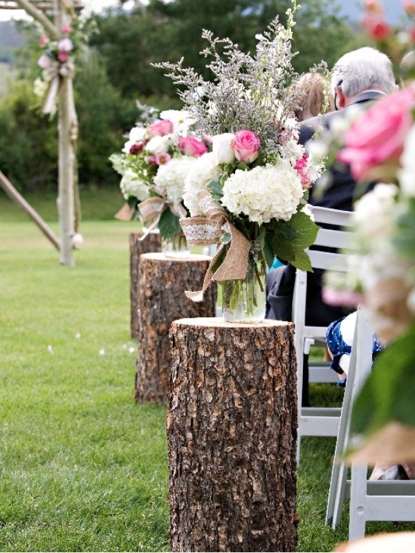Social distancing from wedding aisle using
                      logs as flower stands and spacers