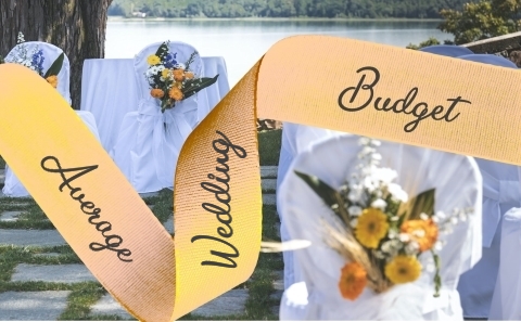 Apricot Ribbon reading
                      Average Wedding Budget over a background of white
                      covered chairs decorated with multicoloured
                      flowers with a river in the background