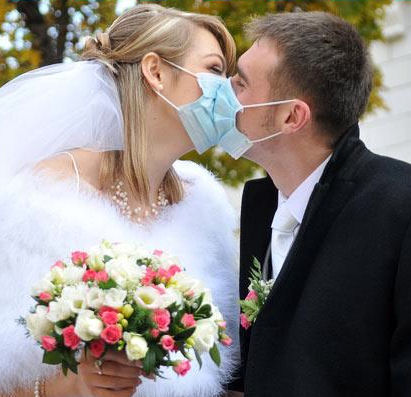 Bride and groom
                      kissing through surgical masks