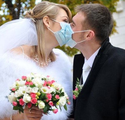 Bride and groom
kissing through surgical masks