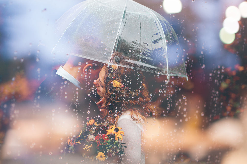 Bride and Groom under an umbrella in pouring
                  rain