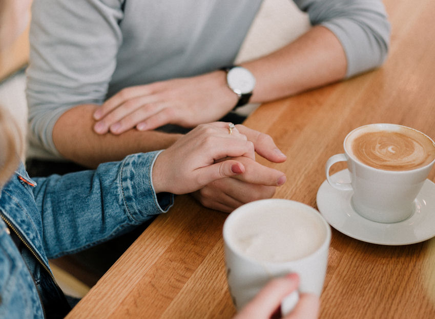 Couple holding hands with cups of coffee