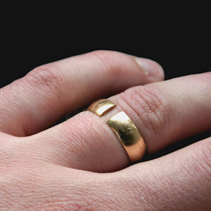 Gold wedding ring with a split in it
                    pictured on a person's ring finger