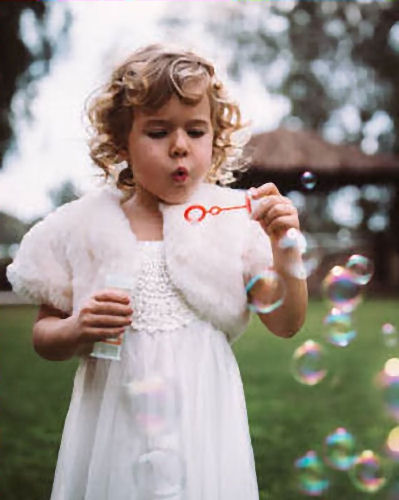 Flower girl blowing bubbles through a red
                      wand