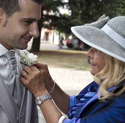 Mother pinning
                      boutonniere on groom's lapel