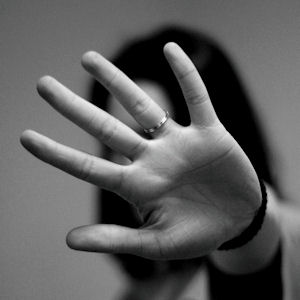 Black and white photo of a woman holding
                        up her hand palm out in the stop gesture