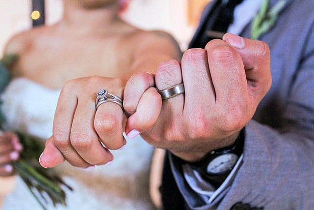 Couple's hands doing a pinky promise with
                      wedding rings on left hands