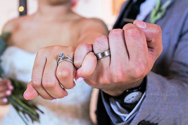 Couple's hands doing a pinky promise with
                      wedding rings on left hands