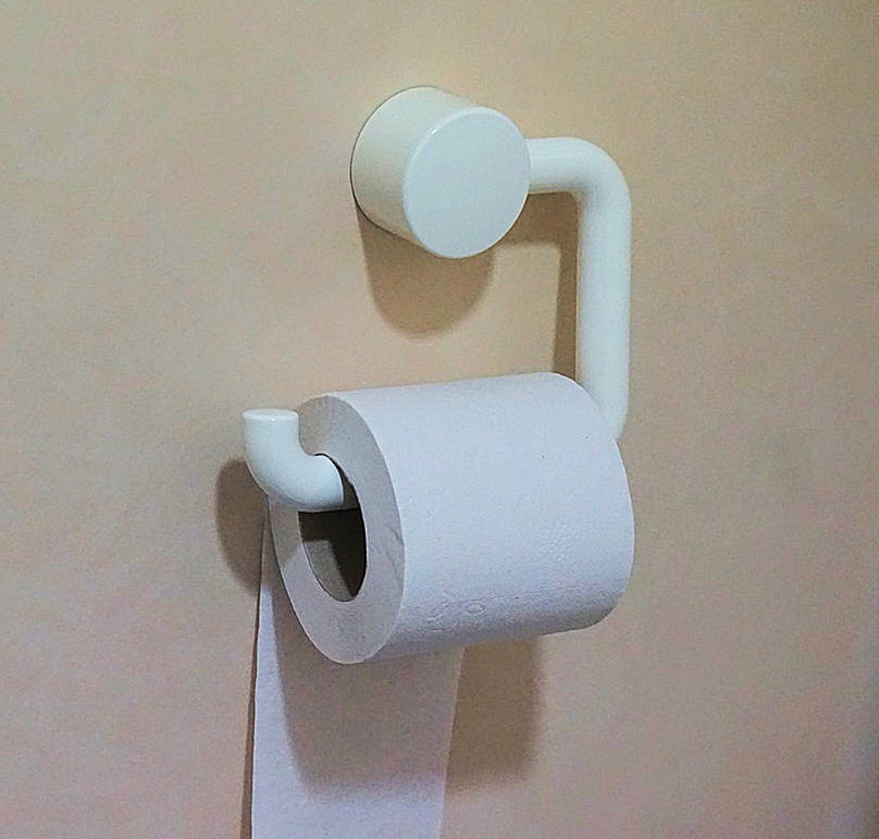 Roll of white toilet
                        paper on white holder against a pinkish wall