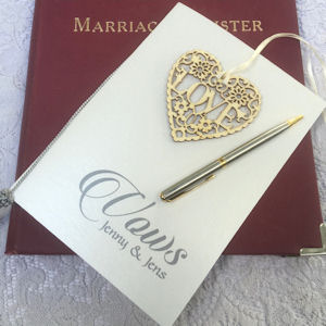 Vows booklet on a Marriage Register with a
                    silver and gold pen and a filigree wooden heart
