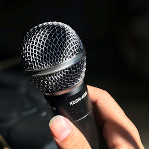 Hand holding a microphone against a dark
                      background