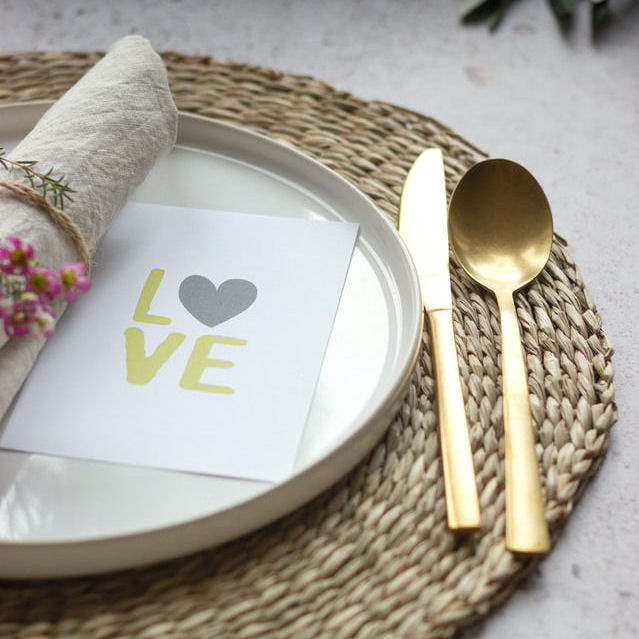 Wedding Reception place
                      setting. Rush mat. Gold knife and spoon. Rolled
                      napkin in napkin ring. Closed menu on plate with
                      heart and the word love printed on it